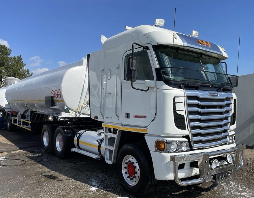 White Freightliner truck with a fuel tanker trailer